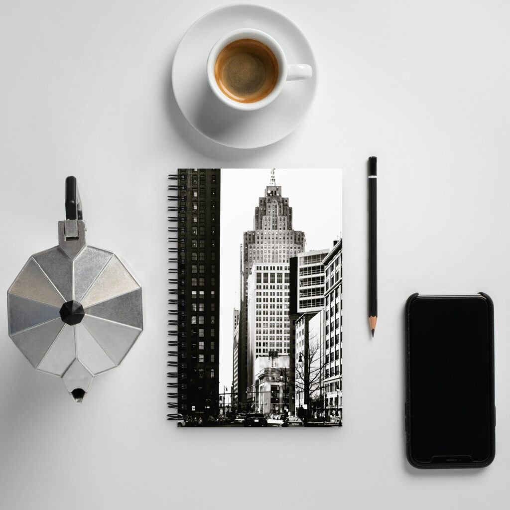 Desk top with Detroit cover on a spiral notebook, coffee and phone